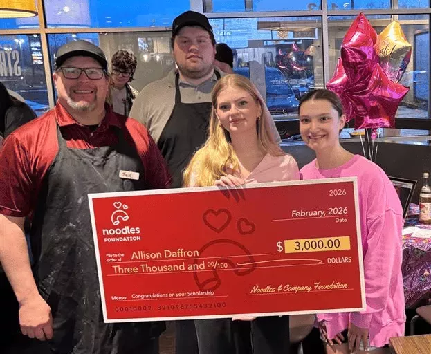 Noodles Foundation winner holding the $3,000 check with family