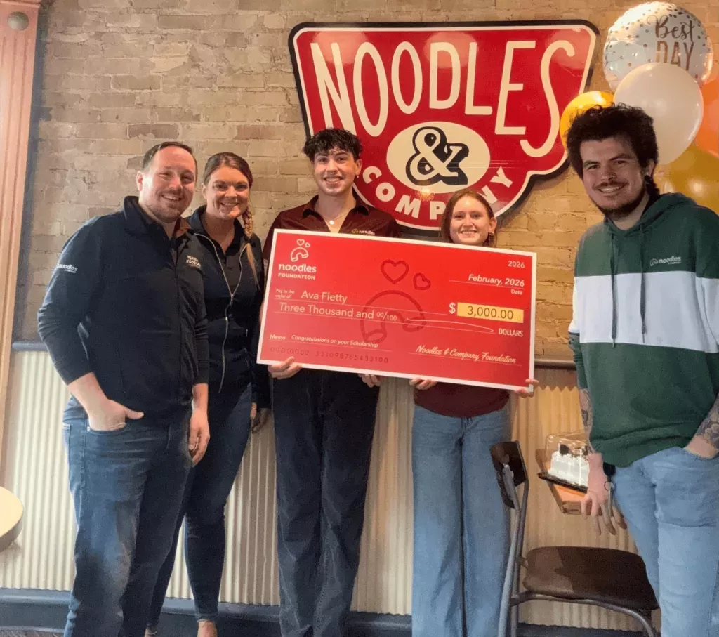 Noodles Foundation winner holding the $3,000 check with family