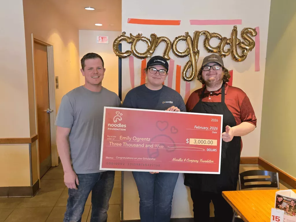 Noodles Foundation winner holding the $3,000 check with family