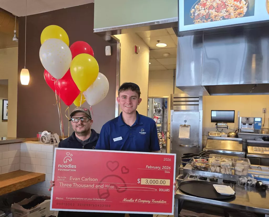 Noodles Foundation winner holding the $3,000 check with family