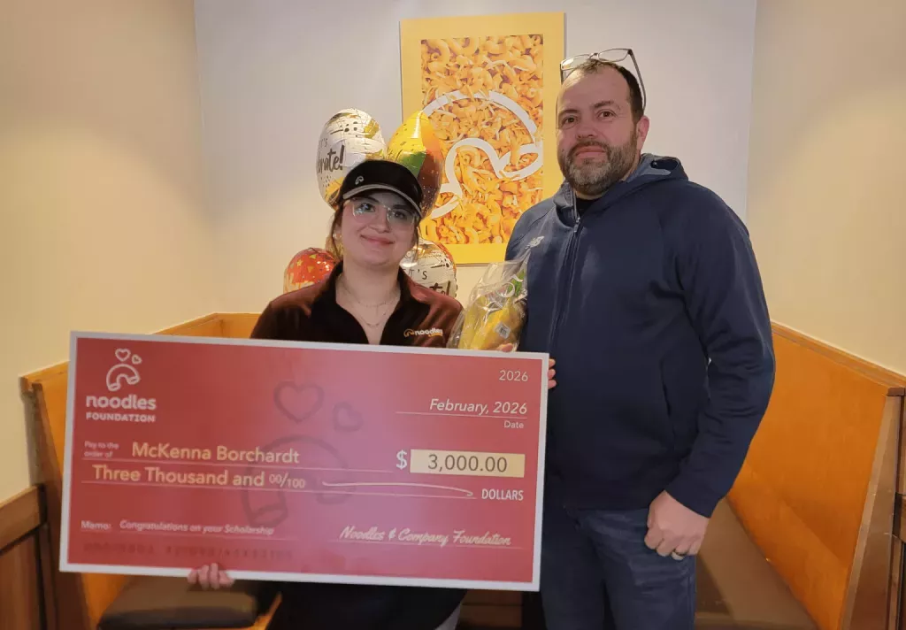 Noodles Foundation winner holding the $3,000 check with family