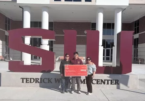 Noodles Foundation winner holding the $3,000 check with family