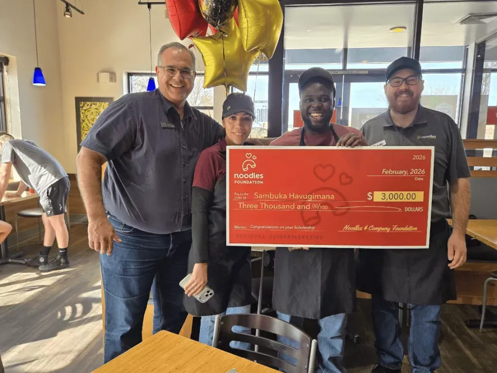 Noodles Foundation winner holding the $3,000 check with family